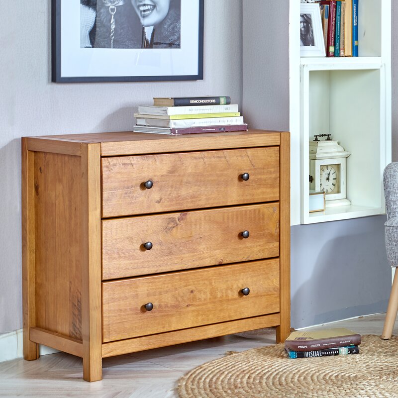 A room with a wood dresser with books on top of it up against a wall with a picture frame hanging nearby.
